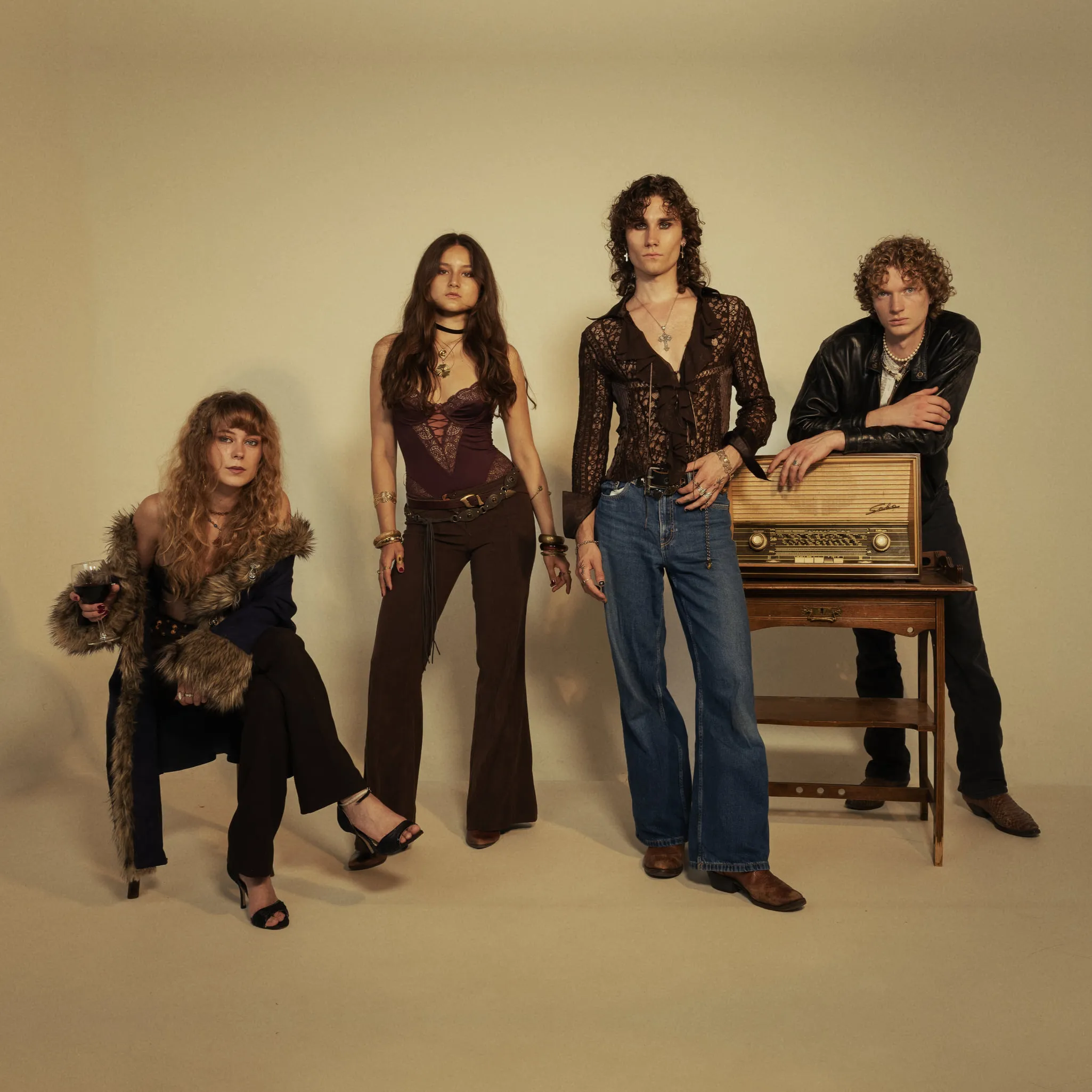 The four members of Corduroy County standing and seated in front of a cream studio sweep, beside a valve radio on a wooden stand.